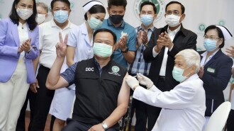 In this photo released by Government Spokesman Office, Thailand's Prime Minister Prayuth Chan-ocha, second right in the background, claps his hands after Thailand's Public Health Minister Anutin Charnvirakul received the first China's Sinovac vaccine at Bamrasnaradura Hospital in Bangkok, Thailand, Sunday, Feb. 28 , 2021. (Government Spokesman Office via AP)