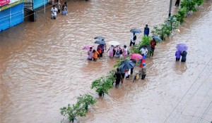 Guwahati: People  make their way through a flooded street after heavy rainfall in Guwahati, Assam on Tuesday. PTI Photo(PTI6_13_2017_000183B)
